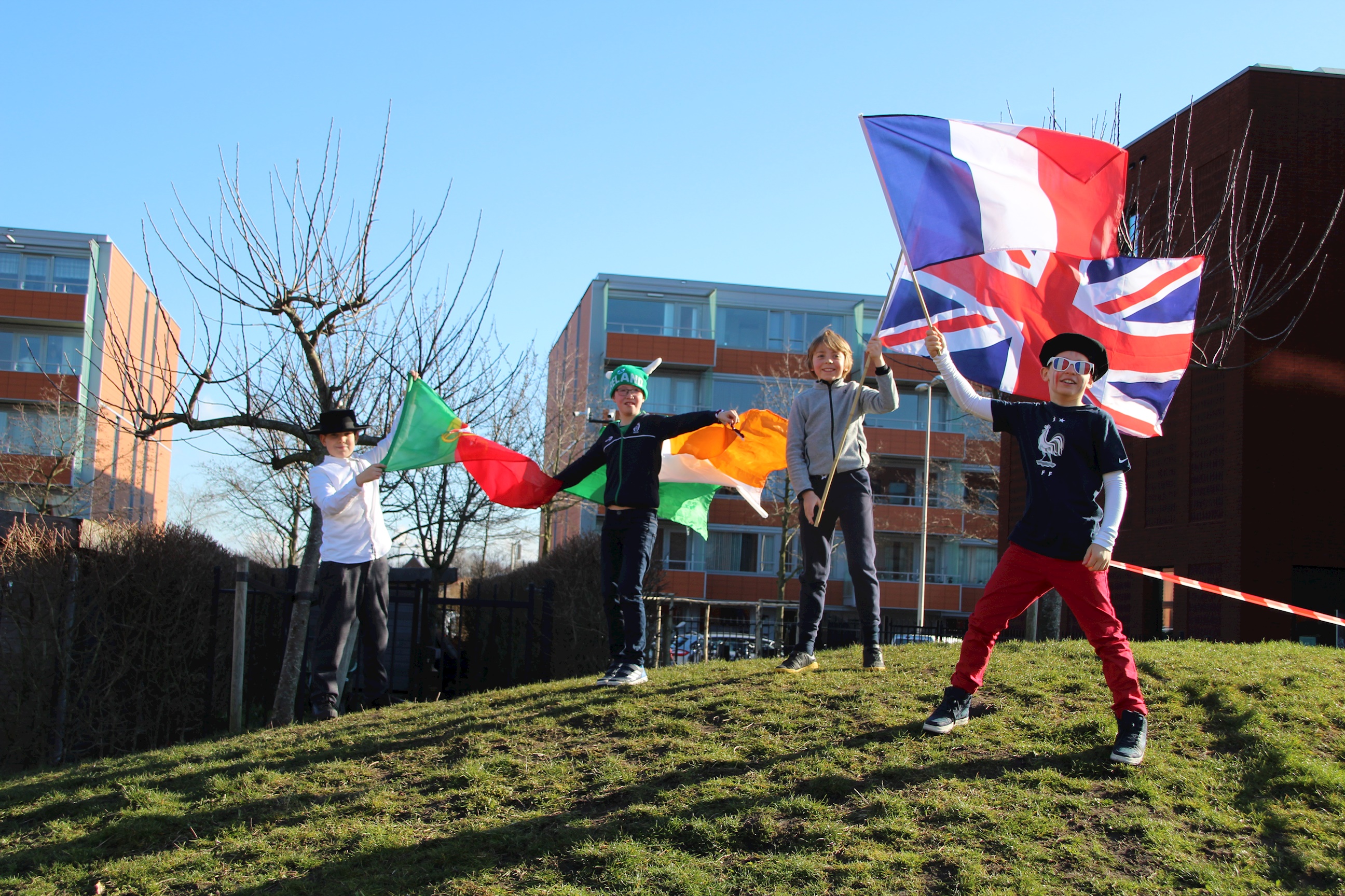 junior school leidschenveen students joyfully waving flags in the green and sunny playground on international day 